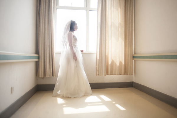 向华穿着婚纱走到医院走廊尽头的窗前，要我给她拍照，阳光落在她身上，令她看起来就像一个真正的新娘。