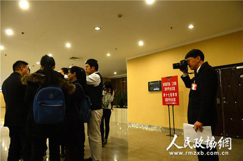 1月23日下午,马光远委员被媒体记着围堵,一旁的朱良(右)委员一手拿提案,一手拿相机记录下这一瞬间.齐波摄_副本