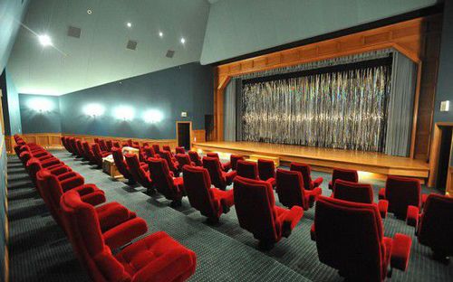 家庭影院中拥有红色天鹅绒椅子和木质舞台。