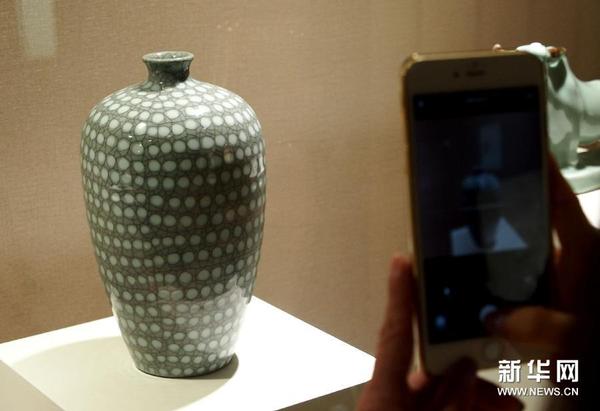 8月7日，观众在中国非遗上海展示中心欣赏龙泉青瓷作品《珍珠梅瓶》。
