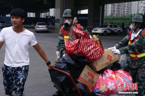 8月18日下午，一队防护人员帮助居民搬运生活用品离开。中新社发 贾国荣 摄