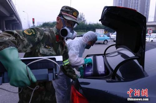 距离天津港爆炸现场最近的小区居民回家取东西，图为8月18日下午，一位武警士兵帮助身穿防护服的居民搬运家用电器。