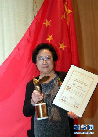 这是2011年9月23日，屠呦呦在美国纽约举行的拉斯克奖颁奖仪式上展示奖杯和证书。