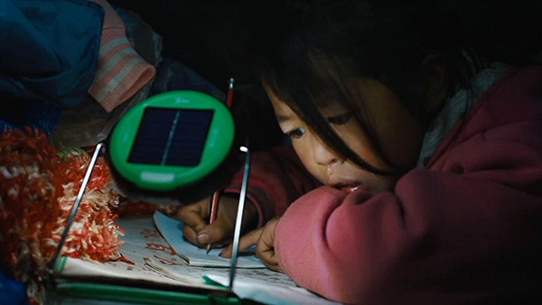 云南鲁甸，一个孩子在上学路上要有光项目组发放的太阳能灯下写作业。