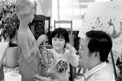 杨恒清带着女儿一起雕刻木雕。 记者 平索茜 摄