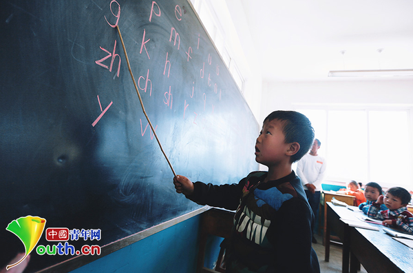 　　6岁的杨严国熟练地读着黑板上的拼音字母。