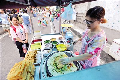 昨日下午，渝北西政校区旁学林路，李玉红在做煎饼，刚开始卖就有学生来买。