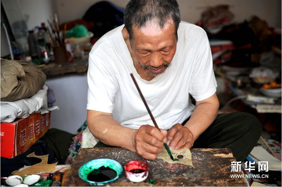 6月5日，张奎老人在为雕刻好的皮影上色