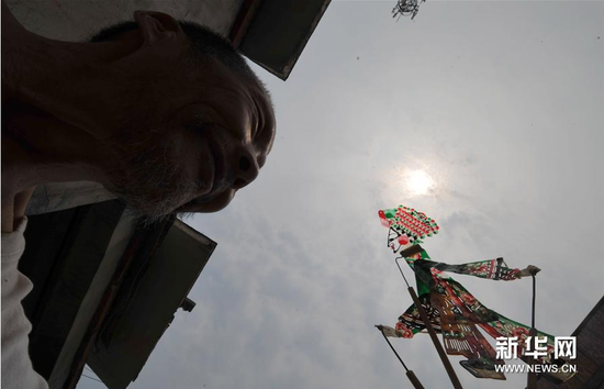 6月5日，张奎老人在屋外展示制作的皮影