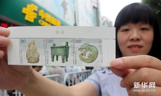 7月13日，一名集邮爱好者在江苏苏州邮政局展示刚购买的《殷墟》特种邮票。