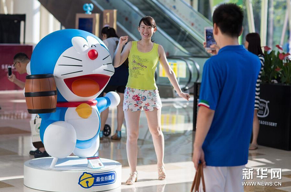 7月31日，一名市民在哆啦A梦卡通造型旁拍照。1