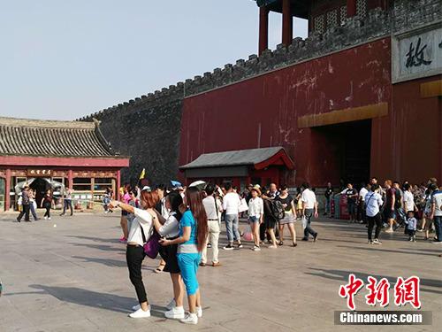 游客在故宫北门外用自拍杆合影。中新网记者 宋宇晟 摄