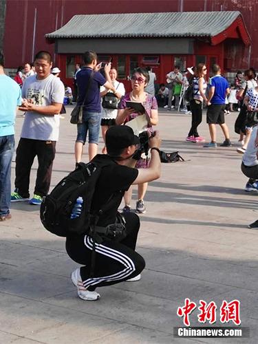 游客在故宫北门外拍照。中新网记者 宋宇晟 摄