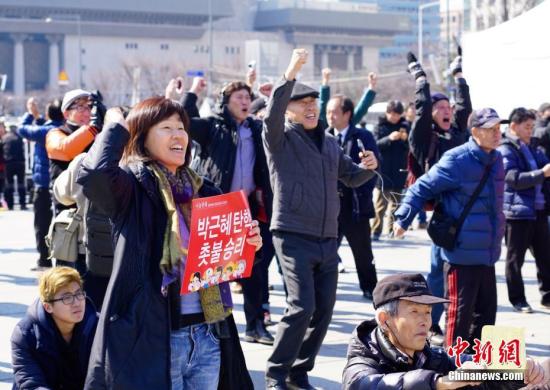 3月10日，在象征着韩国政治中心的首尔光化门广场，民众在听到宪法法院对总统朴槿惠弹劾案的审判结果后欢呼。韩国宪法法院当日作出裁决，宣布弹劾案成立。朴槿惠成为韩国历史上首位被弹劾罢免的总统。<a target='_blank' href='http://www.chinanews.com/'>中新社</a>记者 吴旭 摄