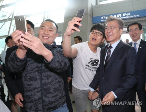 5月12日上午，在仁川机场，文在寅在出席“总统上门活动”前与出境旅客亲切合影。（韩联社） 