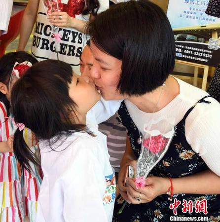 参加此次公益活动的福州一名女童为母亲送上康乃馨花束后，再献深情的一吻，表爱意。　记者刘可耕 摄