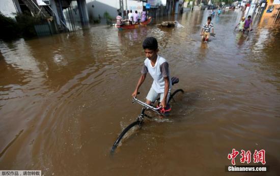 一名儿童在水中骑车，洪水几乎淹没车轮。