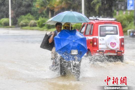 6月13日，惠州惠东县新平大道上，市民家事摩托车加速通过积水路段。　陈骥旻 摄