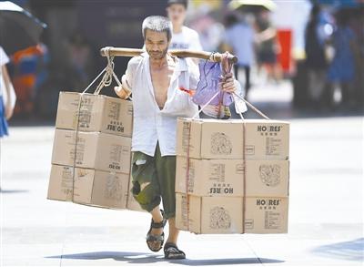 7月28日，一位搬运工在重庆市江北区观音桥商圈顶着烈日搬运货物。 当日，重庆市气象台发布高温红色预警信号，多个区县的最高气温达40℃以上。 新华社记者 王全超 摄