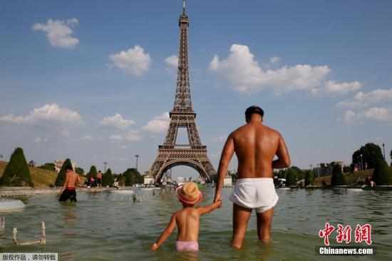 当地时间6月21日，法国巴黎，人们在埃菲尔铁塔前的TROCADERO广场上玩水，以躲避高温。
