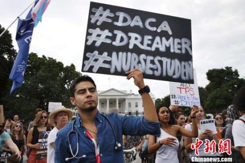 当地时间9月5日，抗议者在白宫外手举标语，反对特朗普政府废除DACA移民计划。