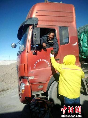 图为现场救援人员为滞留卡车司机送食品。　钟欣 摄