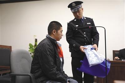 昨日，怀柔法院法庭上，法警向将一辆车卖了8次的被告人刘某出示物证。本版摄影/新京报记者 王飞