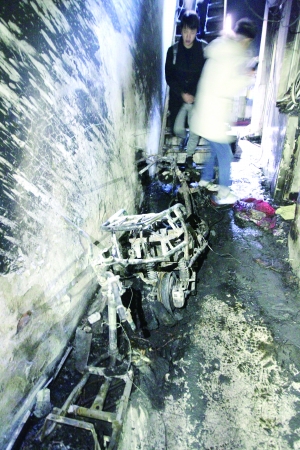 ▲位于楼梯口的两台电动车已被烧得只剩下骨架。图片来源：北京晨报