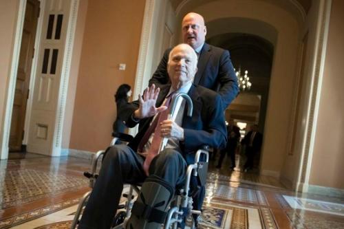 图中坐在轮椅上的为约翰·麦凯恩。(图片来源：美联社)