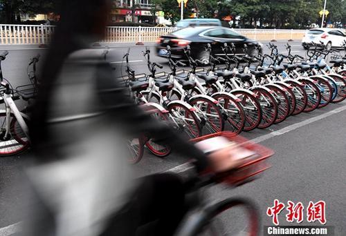 资料图：路人骑着共享单车经过“车堆”。<a target='_blank' href='http://www.chinanews.com/'>中新社</a>记者 张斌 摄