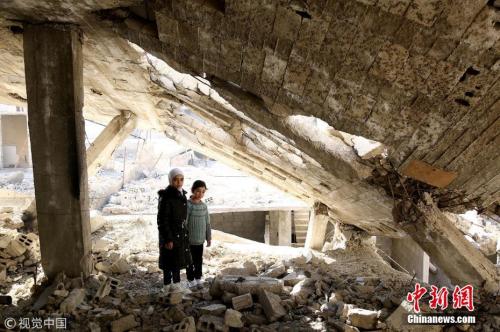 资料图：叙利亚大马士革东古塔区，一对小姐妹站在满目疮痍的家园上。