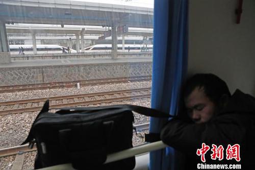一路上旅客们趴在扶手上睡觉，顾不上身边经过的复兴号列车。　殷立勤 摄
