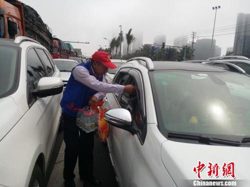 2月21日，海口滨海大道，志愿者向滞留旅客发放食物。　尹海明 摄