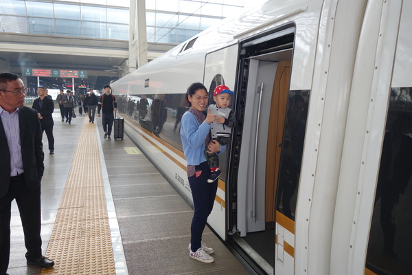 一位年轻的妈妈带着孩子登上G19次“复兴号”高铁