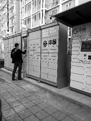 快递员扫码将快递包裹逐一放入柜子中。图片来源：北京晨报