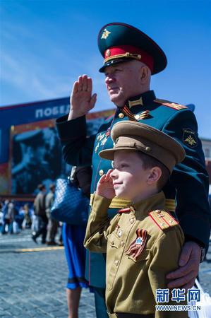 5月9日，在俄罗斯莫斯科，一名老兵与自己的孙子在阅兵结束后合影。