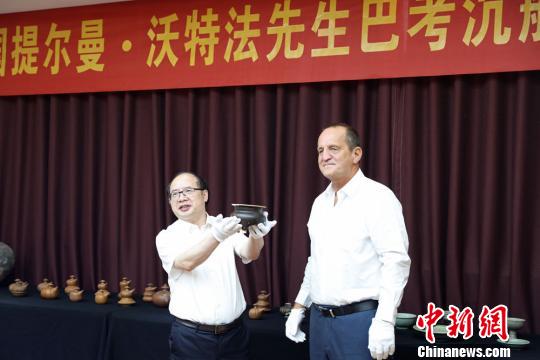  提尔曼-沃特法（右）向湖南省博物馆捐赠巴考沉船代表文物明景德镇窑酱釉三足香炉。湖南省博物馆供图