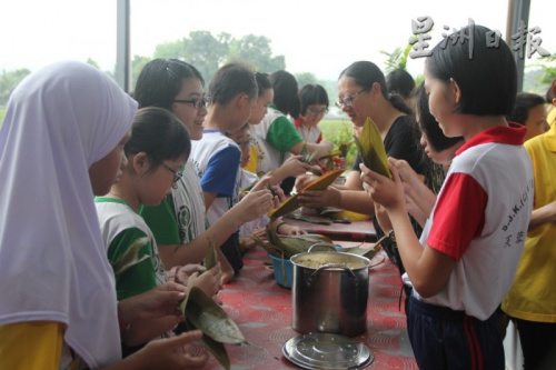在爱心妈妈的协助下，巫华裔学生都参与裹粽子过程，也得知端午节的来历及典故。(马来西亚《星洲日报》)