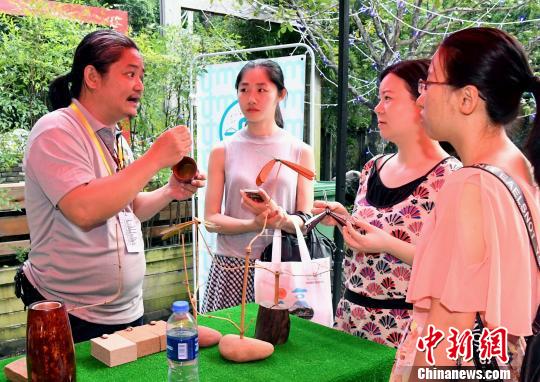 台湾雕刻艺术家、台湾木恋石文化艺术有限公司创办人黄守堃(左一)向观众介绍自己的雕刻作品。记者刘可耕 摄