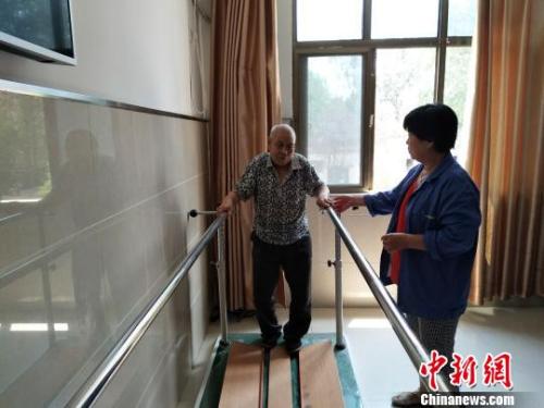 资料图：老人在护工的协助下进行康复训练。陈建华、薛艳伟供图