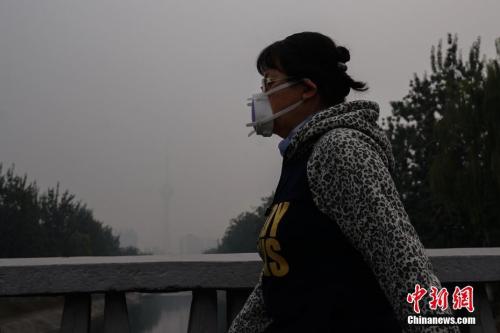 图为10月15日，北京一名市民戴防霾口罩在户外行走，远处的中央电视塔亦被雾霾笼罩。<a target='_blank' href='http://www.chinanews.com/'>中新社</a>记者 崔楠 摄