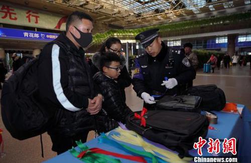 12月28日，北京西站派出所民警为背黑色双肩包的旅客系上个性小标识，以防在通过安检或乘车过程中出现错拿情况。(完) 庞贺雷 摄