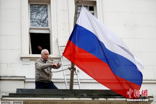 (图4) 当地时间2018年3月14日，一名男子将俄罗斯驻英国大使馆门前的俄罗斯国旗取下。