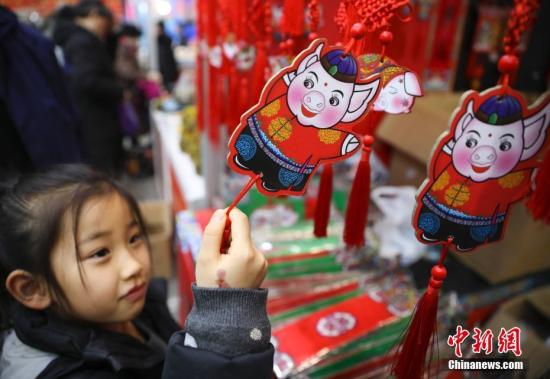 1月23日，正在北京全国农业展览馆举办的2019老北京年货大集人头攒动、热闹非凡。全国各地区优质特色产品及民俗文化在此一一呈现，给北京市民带来精彩纷呈的购物体验。图为小女孩被年货大集上的猪年福牌吸引。<a target='_blank' href='http://www.chinanews.com/'>中新社</a>记者 赵隽 摄