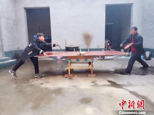 图为刘奉智父亲用自制的乒乓球台陪刘奉智打乒乓球。　郝学娟 摄