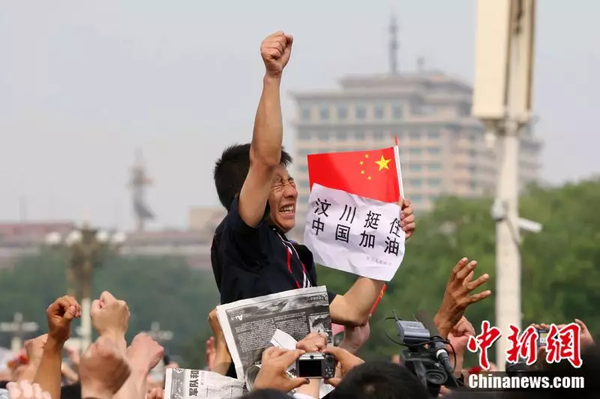 2008年5月19日，北京天安门广场上的民众为地震遇难者默哀，一位来自四川的男子高举右手为家乡加油。中新社记者 富田 摄