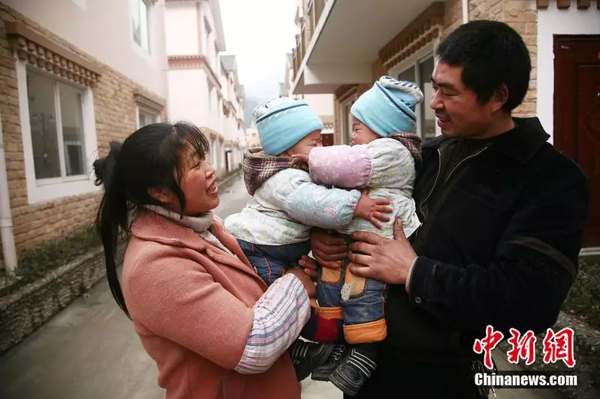 2011年1月28日，震中映秀镇张家坪村村民搬进了新家，再生育家庭抱着双胞胎拍摄合影。中新社记者 张浪摄