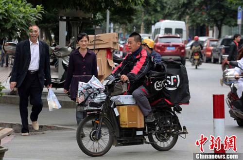 一名快递公司送货员正骑着满载快件的电单车在市区内送货。李俊锋 摄