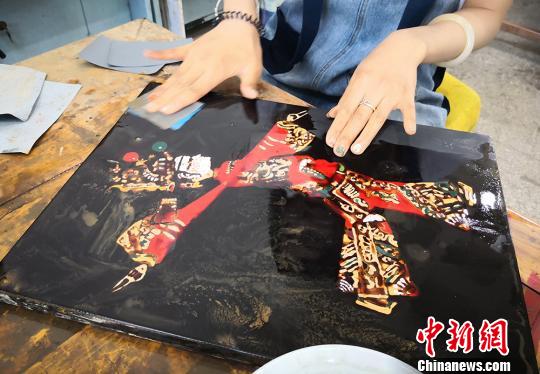 图为学生正在打磨以传统皮影为元素的漆画作品。　刘玉桃 摄