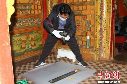 图为西藏自治区古籍保护中心古籍保护部副主任才洛采集古籍影像信息。　赵朗 摄